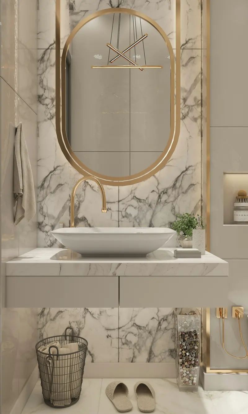 Baño con revestimiento de mármol, espejo ovalado dorado y lavabo sobre encimera