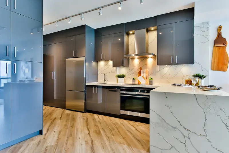 Cocina con muebles grises, isla de mármol y suelo de madera