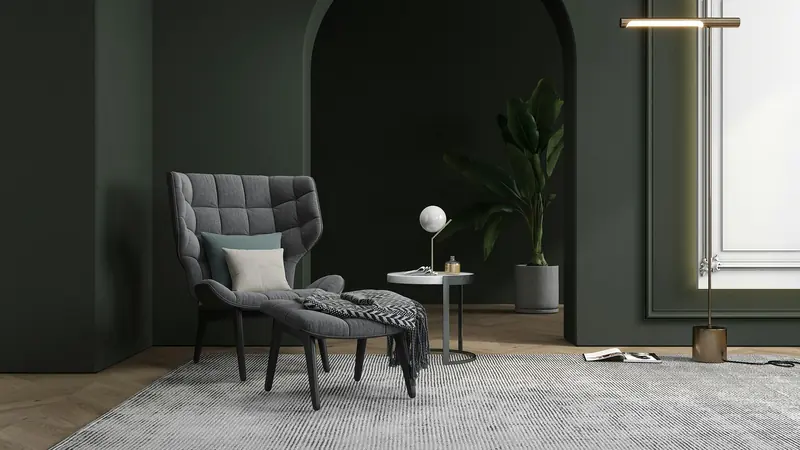 Rincón de lectura con pared verde oscuro y sillón gris